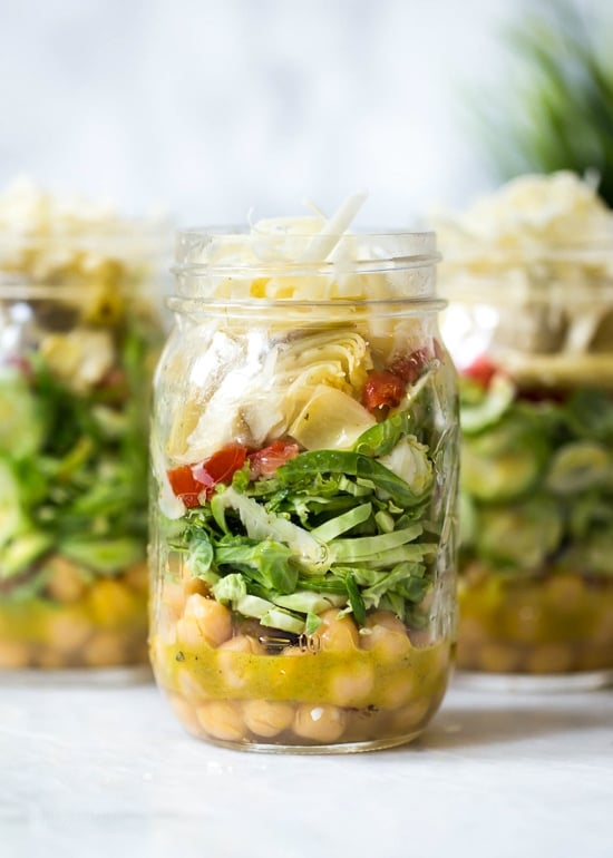 A quick and easy lunch solution for the week – salad in a jar made with shaved Brussels sprouts, chickpeas, marinated artichokes, sun dried tomatoes and Asiago cheese. Perfect to pack for work or anywhere you need a portable lunch on-the-go! To serve you simply shake it up and pour it into a bowl.