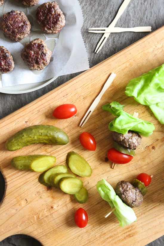 Mini burgers with bacon, layered on a bamboo skewer with lettuce, tomatoes and pickles! Who can resist your favorite foods on a stick – not me! These burger bites make the perfect low-carb appetizer to please everyone from age six to age sixty, just set out some ketchup and mustard for dipping and watch them disappear.