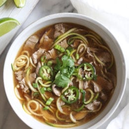 A quick, flavorful Vietnamese-inspired nood-less pho subs zucchini for rice noodles. So easy, the steak is sliced thin and cooks less than a minute in the ginger-garlic beef broth. Top this with fresh lime, basil, cilantro, jalapeno and scallions and you have one tasty soup!