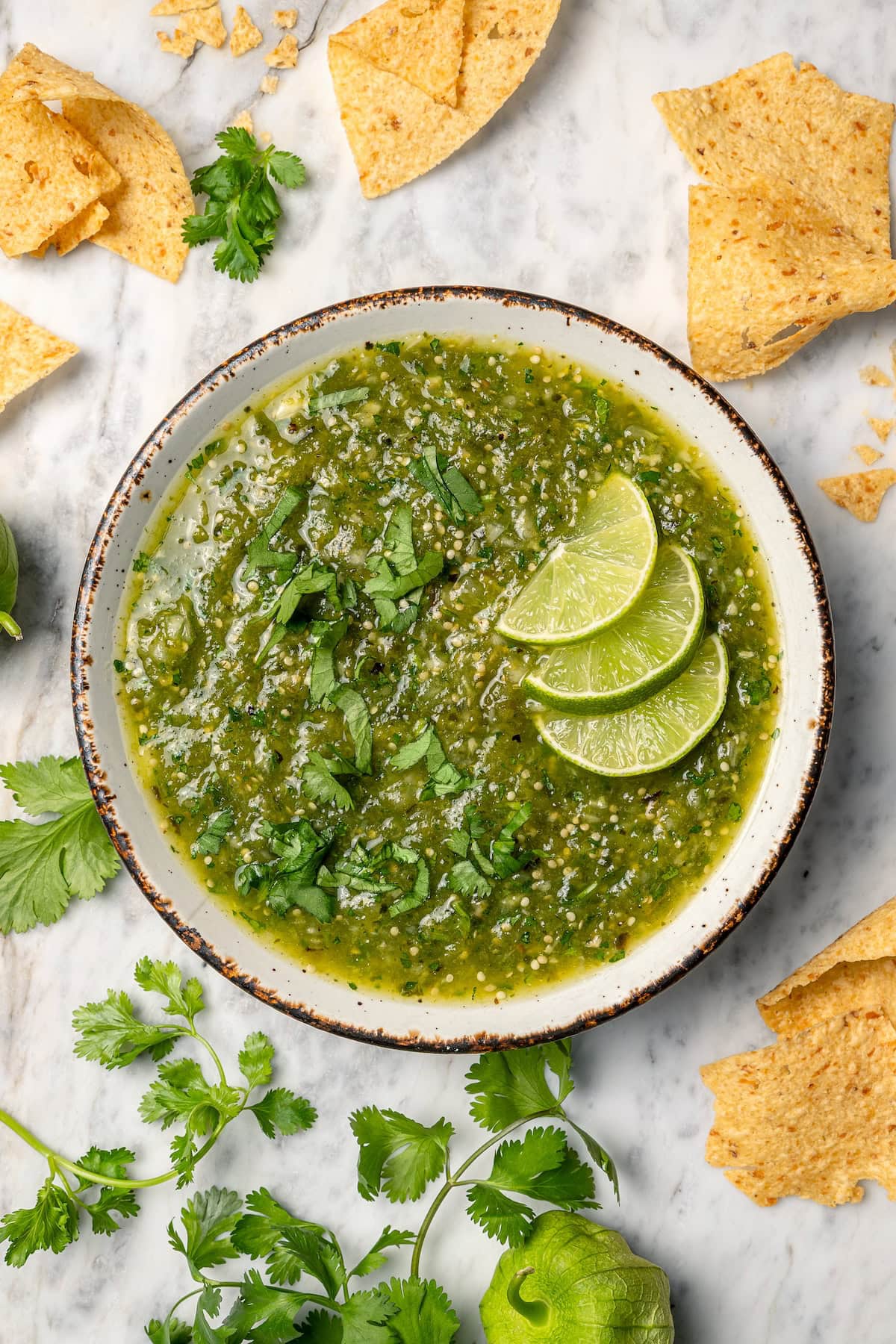 Roasting the tomatillos and peppers first makes this homemade salsa verde recipe extra delicious. Easy to make and better than store-bought! Overhead view of salsa verde in bowl with 3 lime slices