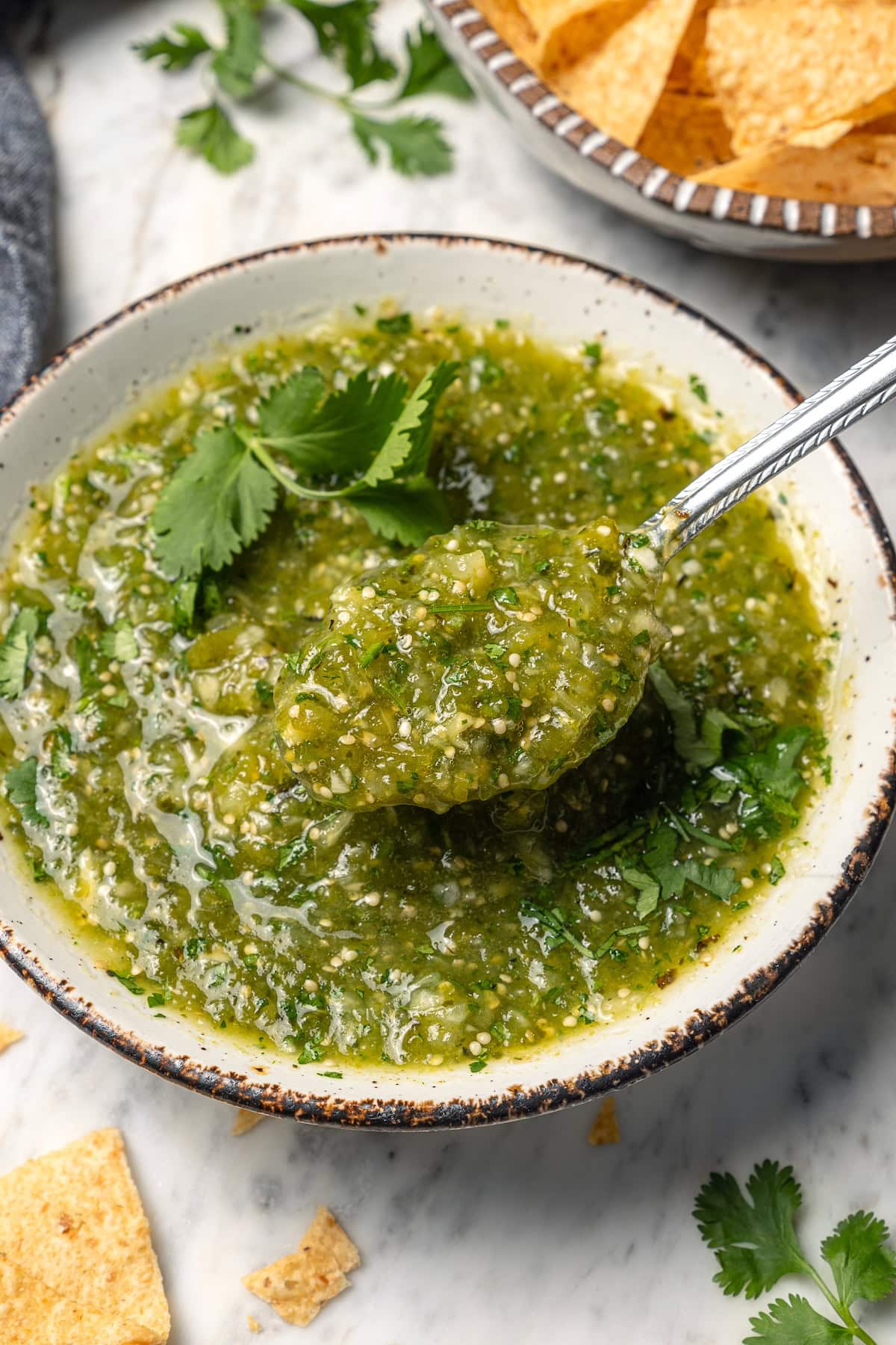 Roasting the tomatillos and peppers first makes this homemade salsa verde recipe extra delicious. Easy to make and better than store-bought! Spoonful of salsa verde in bowl
