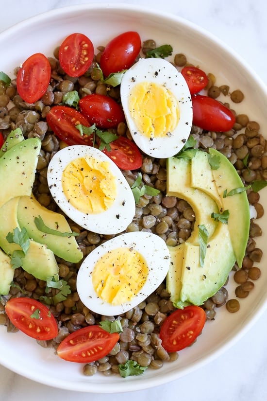 This easy foolproof stove top method for making hard boiled eggs gives you PERFECT results every time. The best way to hard boil eggs! Overhead view of lentil salad with avocado and hard boiled eggs