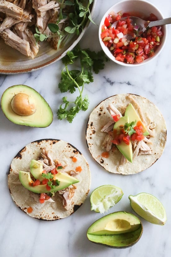 This Instant Pot Cuban Pork Recipe features tender shredded pork marinated in a garlic, cumin and citrus marinade, then cooked to perfection. Tacos made with shredded pork, avocado, and salsa