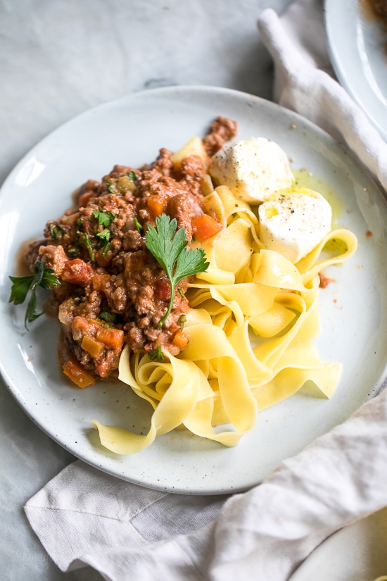 Instant Pot Bolognese sauce is full of flavor and ready in one hour! See how easy it is to make a classic meat sauce in your pressure cooker. Overhead view of a plate of pasta bolognese garnished with parsley and cheese.