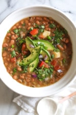 Bowl of instant pot pinto beans with avocado on top.