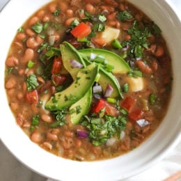 Bowl of instant pot pinto beans with avocado on top.
