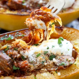 A forkful of spaghetti squash lifted from a roasted spaghetti squash half stuffed with beef and mushroom ragu.