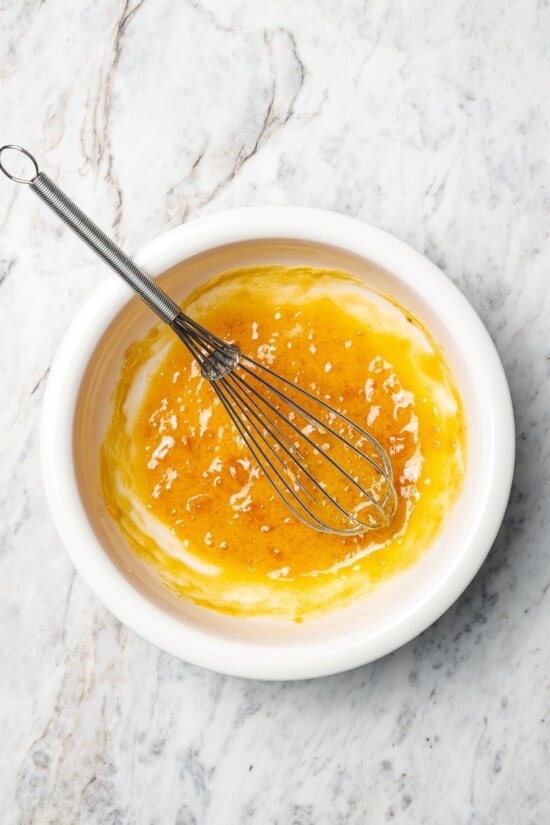 Slow Cooker Ham is the easiest main dish for the holidays! A two-ingredient glaze and a crockpot are all you need for moist, flavorful ham. Apricot and Dijon glaze in bowl with whisk.