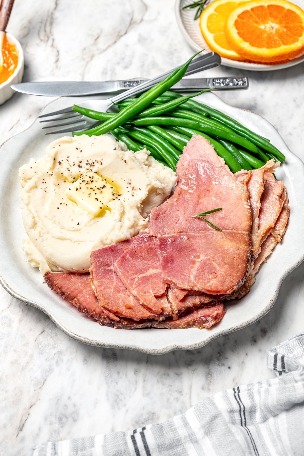 Slow Cooker Ham is the easiest main dish for the holidays! A two-ingredient glaze and a crockpot are all you need for moist, flavorful ham. Slices of slow cooker ham on plate with mashed potatoes and green beans.