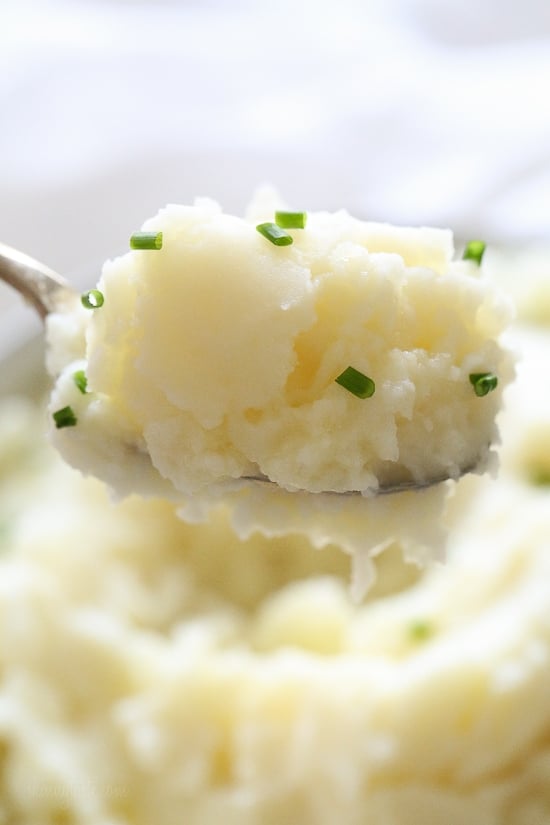 Make creamy Instant Pot mashed potatoes in a fraction of the time! This healthy pressure cooker potatoes recipe is ready in 20 minutes. A spoonful of Instant Pot mashed potatoes sprinkled with chopped chives, with more mash in the background.
