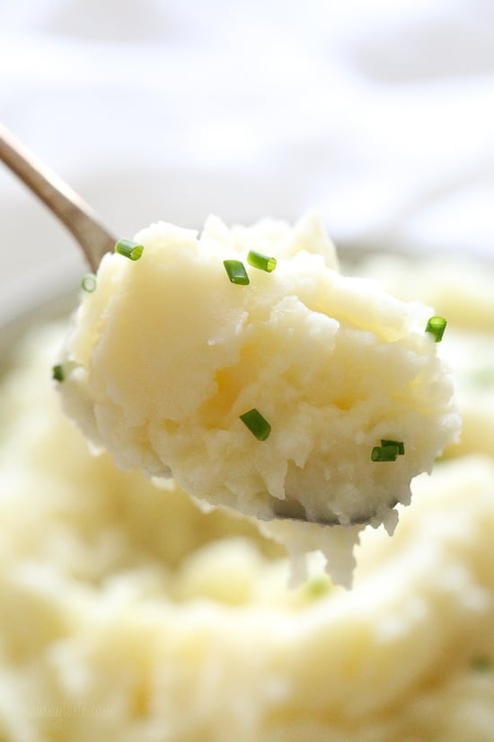 Make creamy Instant Pot mashed potatoes in a fraction of the time! This healthy pressure cooker potatoes recipe is ready in 20 minutes. A spoonful of Instant Pot mashed potatoes sprinkled with chopped chives, with more mash in the background.
