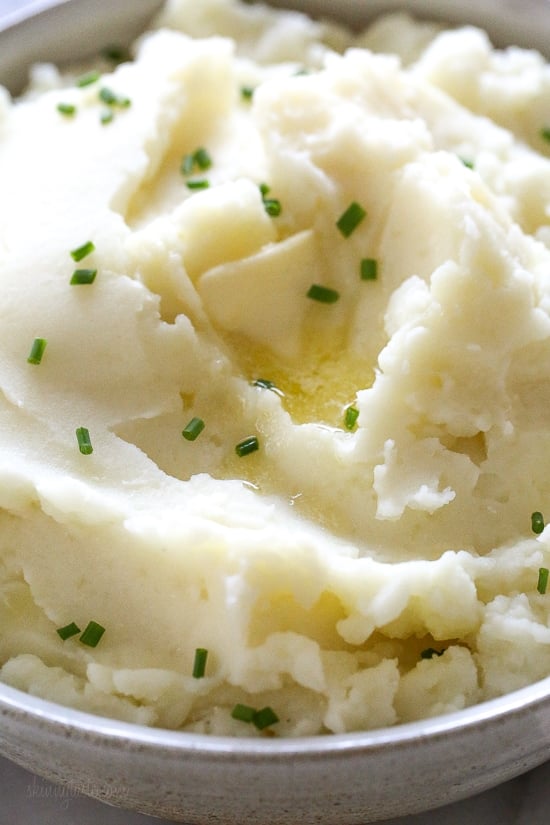 Make creamy Instant Pot mashed potatoes in a fraction of the time! This healthy pressure cooker potatoes recipe is ready in 20 minutes. Close up of a bowl of creamy Instant Pot mashed potatoes topped with chopped chives.