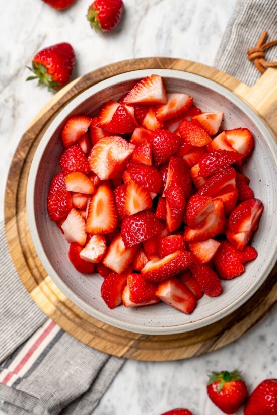 This healthy strawberry crisp recipe is perfectly portioned into individual servings, with a delicious nutty topping. So easy to make too! Fresh quartered strawberries in bowl