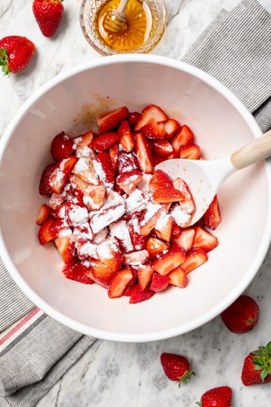 This healthy strawberry crisp recipe is perfectly portioned into individual servings, with a delicious nutty topping. So easy to make too! Stirring cornstarch into strawberries in bowl