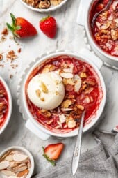 Overhead view of strawberry crisp in bowl with scoop of vanilla ice cream