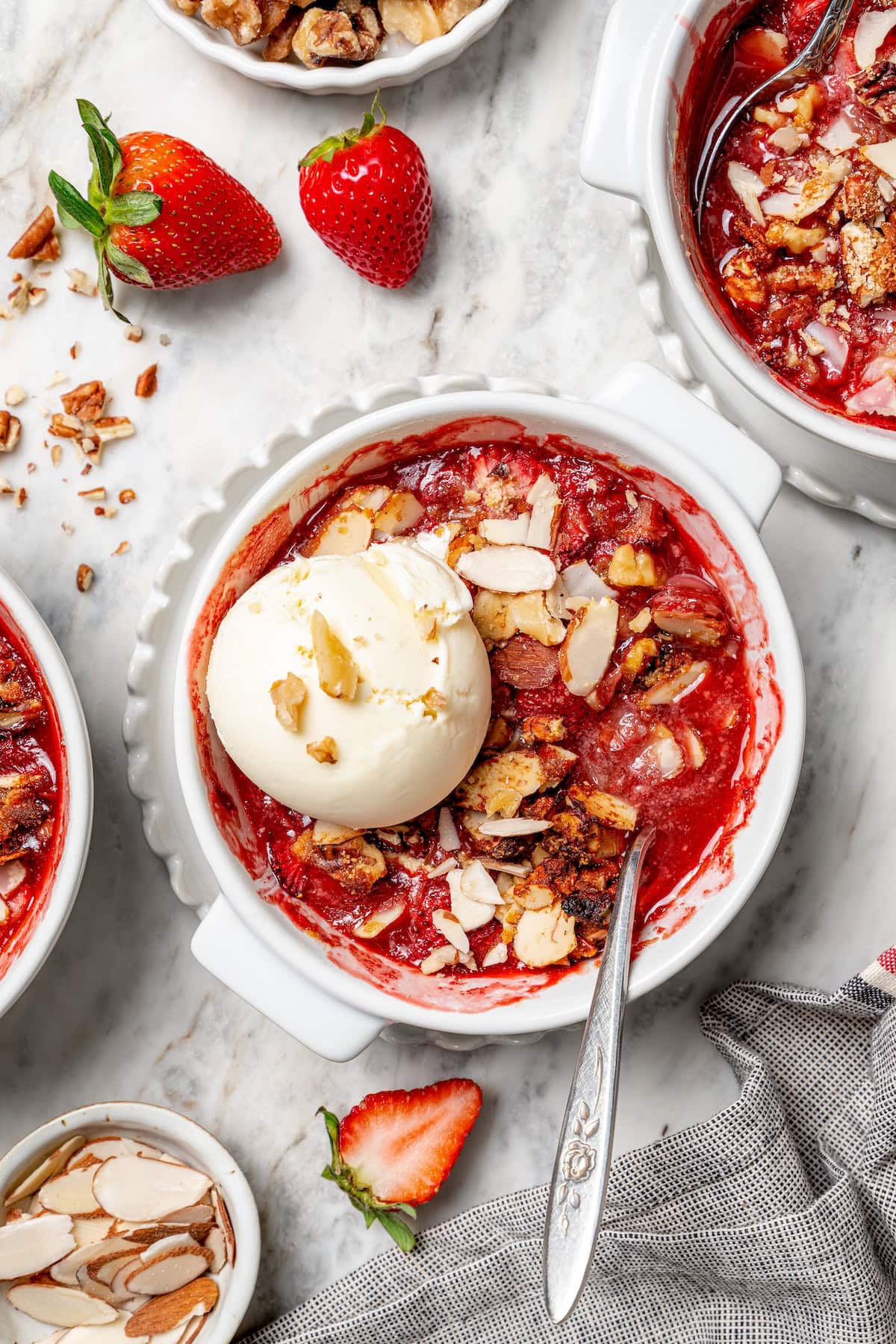 Overhead view of strawberry crisp in bowl with scoop of vanilla ice cream