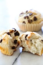 Healthy chocolate chip muffins on marble counter, with one muffin torn in half to show light, fluffy texture