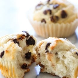Healthy chocolate chip muffins on marble counter, with one muffin torn in half to show light, fluffy texture