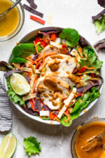 Grilled Chicken Salad with greens and vegetables are tossed in a honey-lime vinaigrette and topped with a delicious peanut sauce.