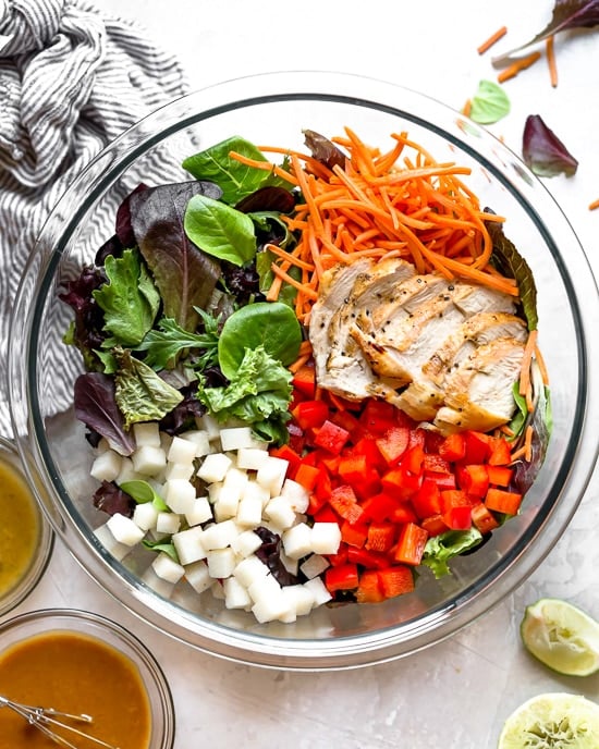 Grilled Chicken Salad with greens and vegetables are tossed in a honey-lime vinaigrette and topped with a delicious peanut sauce.