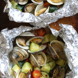 Grilled little neck clams cooked in foil packets with zucchini and tomatoes in a garlic white wine sauce, so fast and easy, perfect to make all summer long!
