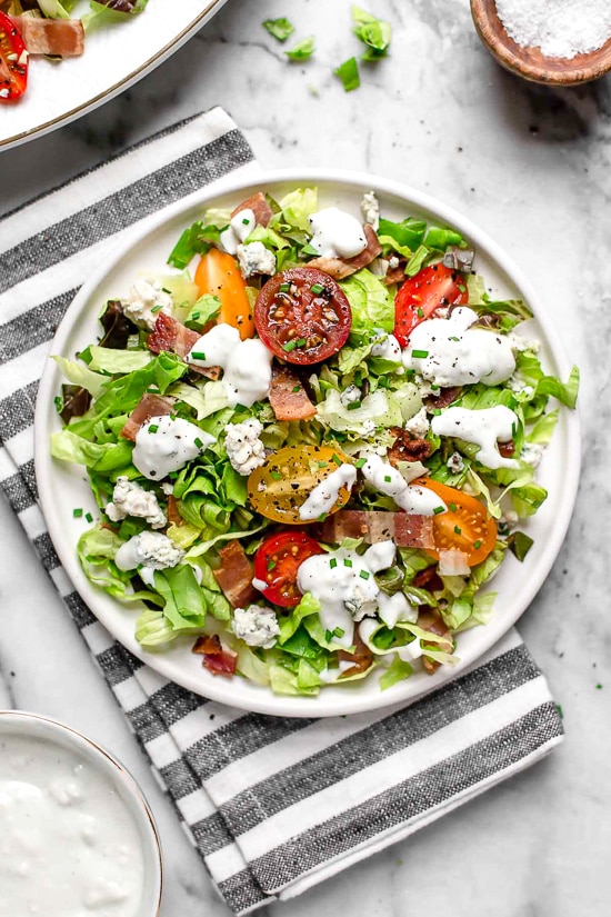 Classic wedge salad meets chopped salad in this easy side salad dish made with lettuce, bacon, blue cheese and chives with a light homemade blue cheese dressing.
