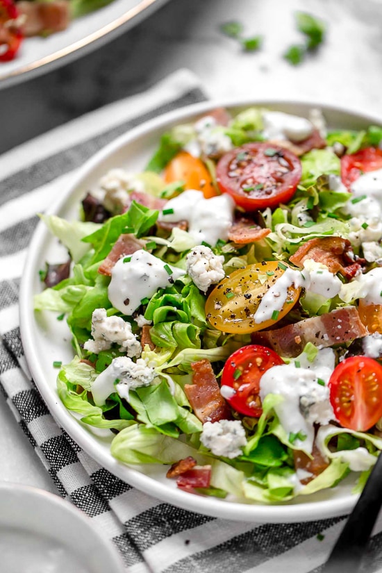 Classic wedge salad meets chopped salad in this easy side salad dish made with lettuce, bacon, blue cheese and chives with a light homemade blue cheese dressing.