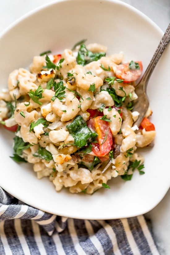 Greek Mac and Cheese, a healthy twist on a comfort food classic made in a creamy cheese sauce with whole wheat pasta, tomatoes, spinach, olives and Feta cheese.