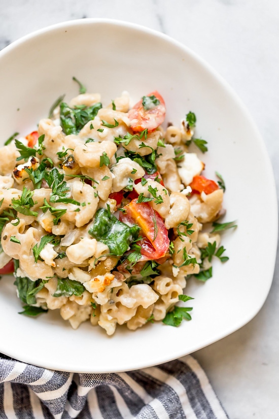 Greek Mac and Cheese, a healthy twist on a comfort food classic made in a creamy cheese sauce with whole wheat pasta, tomatoes, spinach, olives and Feta cheese.