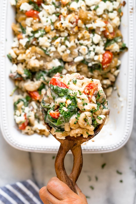 Greek Mac and Cheese, a healthy twist on a comfort food classic made in a creamy cheese sauce with whole wheat pasta, tomatoes, spinach, olives and Feta cheese.