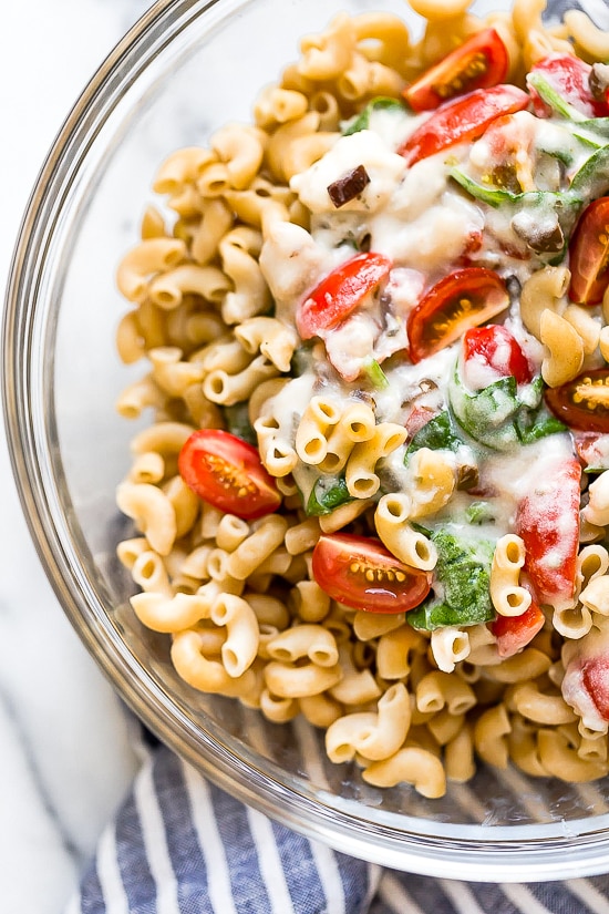 Greek Mac and Cheese, a healthy twist on a comfort food classic made in a creamy cheese sauce with whole wheat pasta, tomatoes, spinach, olives and Feta cheese.