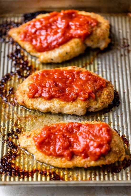 Top baked chicken with marinara sauce and cheese.