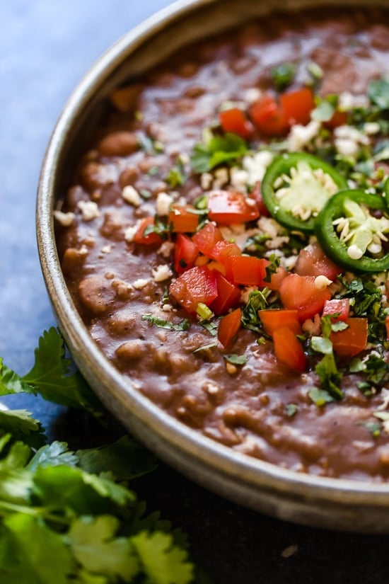 These Instant Pot Refried Beans are a simple, healthy, and fat-free version of the classic Mexican side dish. No oil or lard required! Close up of a bowl of Instant Pot refried beans
