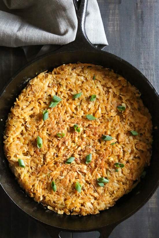 Here's how to make hash browns that are beautifully browned, always crispy, and perfectly seasoned. This recipe won't let you down! Overhead view of crispy hash browns in cast iron skillet