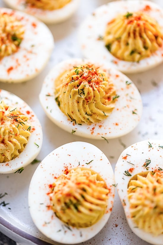 These Instant Pot Deviled Eggs are quick and easy, with a creamy egg yolk filling and a hint of paprika on top. Perfect for potlucks! Close up of deviled eggs on a platter