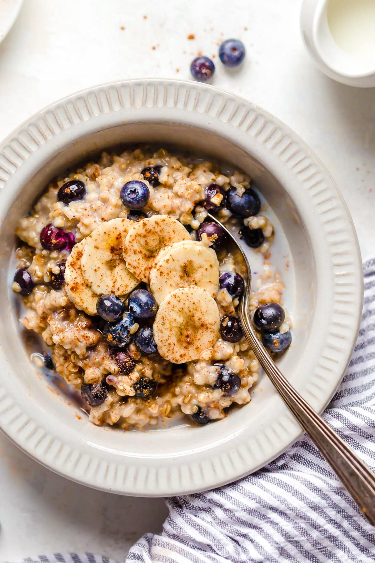 A warm and heart healthy breakfast, making Steel Cut Oats in the Instant Pot is so much faster than making them on the stove! A spoon in a bowl of oats with blueberries and bananas.