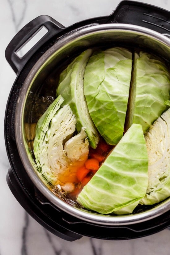 This easy Instant Pot Corned Beef and Cabbage recipe comes out perfectly tender every time! The perfect St. Patrick's Day dinner. Cabbage in an instant pot on top of carrots and beef brisket