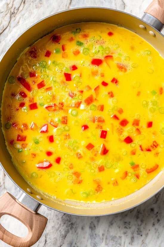 These easy freezer breakfast burritos are a delicious, protein-packed way to start the day with scrambled eggs, veggies, bacon and cheese. Eggs and veggies in pan