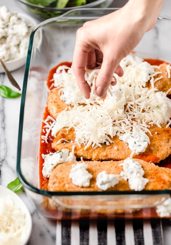 This easy Chicken Parmesan Lasagna is a combination of two classic dishes. It's the perfect family-friendly dish to feed a large crowd! Cheese on top of chicken cutlets in a casserole dish