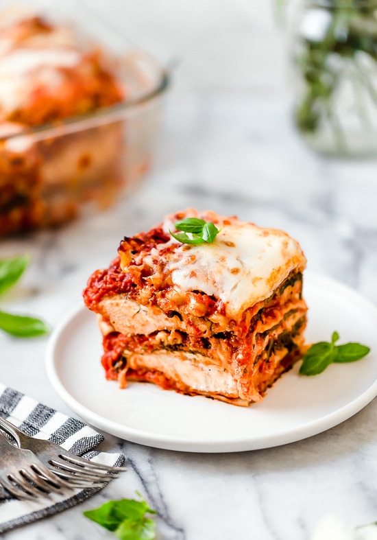 This easy Chicken Parmesan Lasagna is a combination of two classic dishes. It's the perfect family-friendly dish to feed a large crowd! A slice of chicken parmesan lasagna on a plate