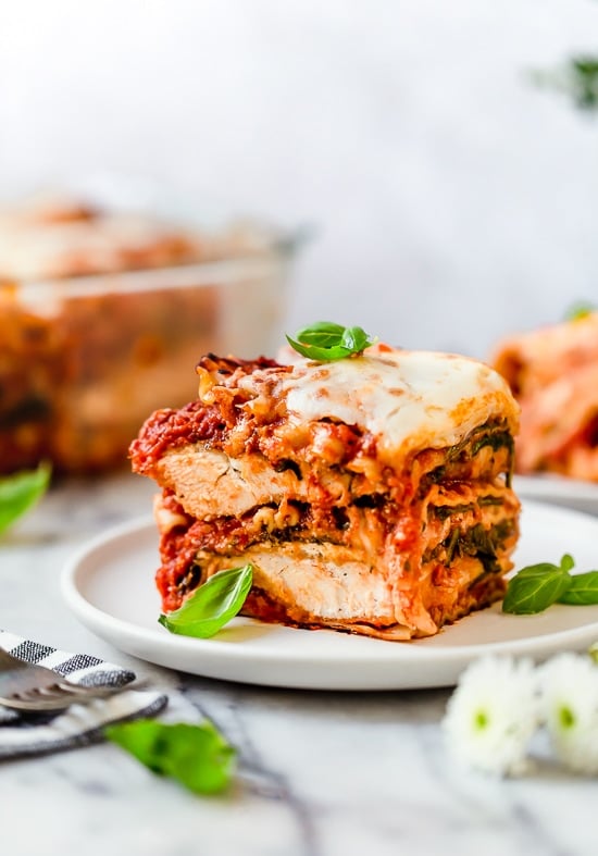 This easy Chicken Parmesan Lasagna is a combination of two classic dishes. It's the perfect family-friendly dish to feed a large crowd! A slice of chicken parmesan lasagna on a plate