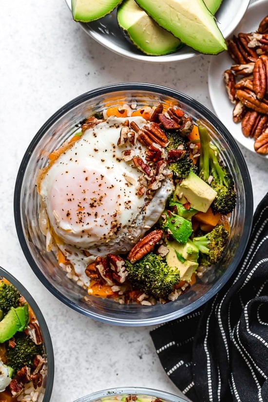 This easy Buddha bowl pairs a brown rice base with roasted broccoli, butternut squash, creamy avocado, fried eggs, and pecans. So delicious! Overhead view of Buddha bowl with fried egg