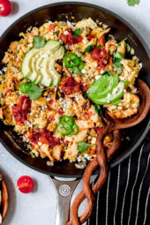 Overhead view of Tex Mex migas in skillet with sliced avocado