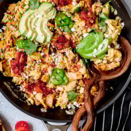Overhead view of Tex Mex migas in skillet with sliced avocado
