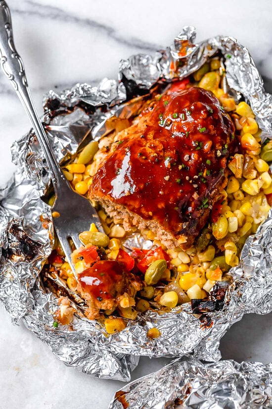 These Campfire Meatloaf Foil Packets are great for camping, glamping or for an easy weeknight dinner. Each packet has individual turkey meatloaves slathered with BBQ sauce cooked over summer succotash.