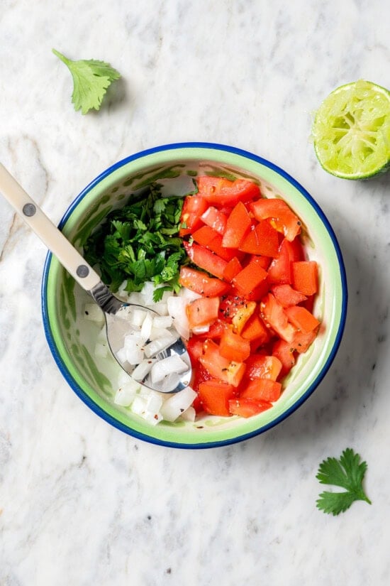 Crispy air fryer chicken chimichangas are an easy and healthier twist on the classic! Filled with cheese, green chiles, and seasoned chicken. Pico de gallo ingredients in bowl