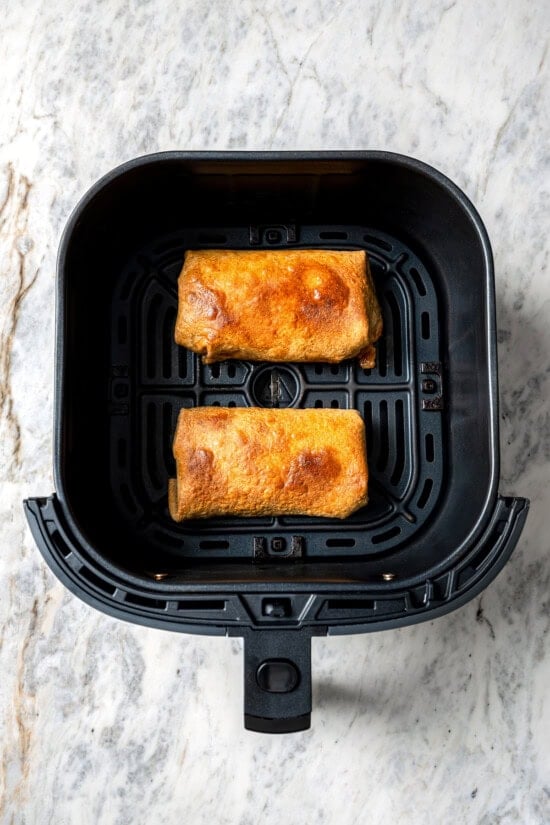 Crispy air fryer chicken chimichangas are an easy and healthier twist on the classic! Filled with cheese, green chiles, and seasoned chicken. Top-down view of crispy chicken chimichangas in air fryer