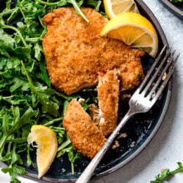 Crisp, golden, delicious Air Fryer Chicken Milanese with Baby Arugula and lemon wedges is one of my favorite dinner recipes!