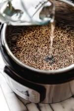 Water is added to an Instant Pot filled with uncooked quinoa.