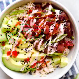 Spicy Tuna Poke Bowls made with chunks of fresh tuna, avocado, cucumbers, spicy mayo, scallions cut on the bias served on a bed of steamed rice.